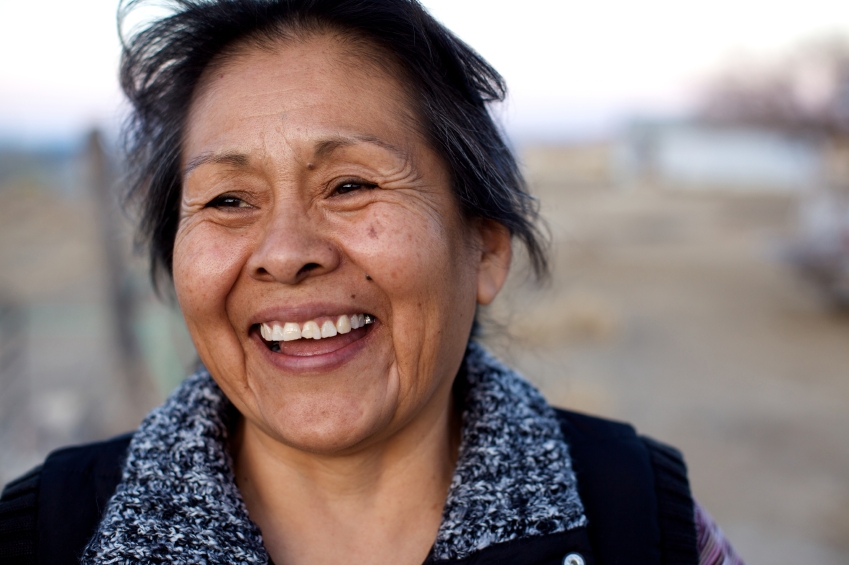 Headshot of woman outside, smiling, looking to the side of the camera